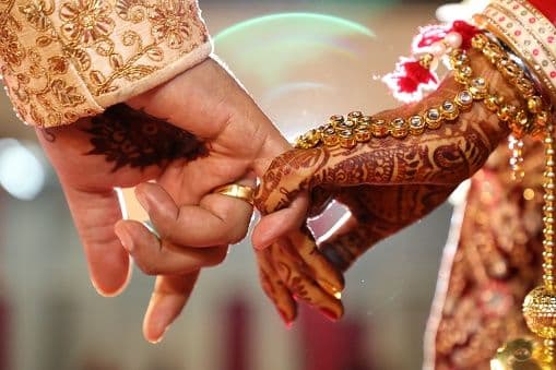 Indian bride and groom holding hands with mehendi